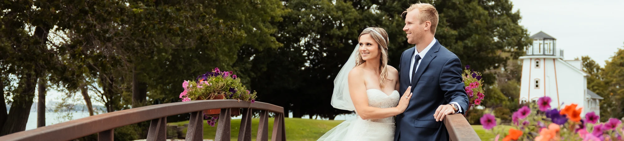 Married couple on bridge with lighthouse in background